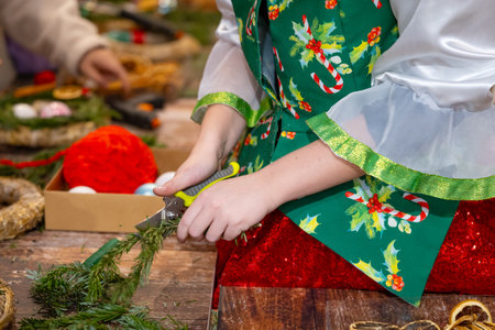 Close-up of the hands of a girl in a green dress cutting a Christmas treeの写真素材