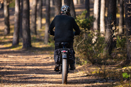 Rear view of a man riding a mountain bike in the forestの写真素材