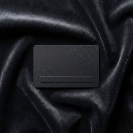 A sleek, minimalist black business card mockup is presented on a backdrop of rich, flowing black silk fabric, creating a sophisticated and luxurious aesthetic. The card is perfectly centered, offering a prime space for branding.の素材