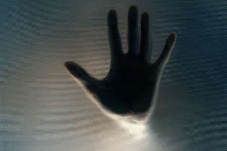 Hand through the semi-transparent glassの写真素材