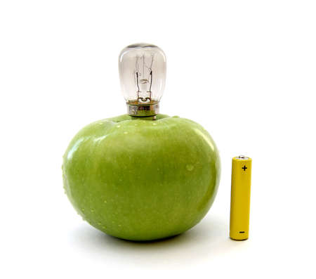 Green apple with a lamp and a battery isolated over white backgroundの写真素材
