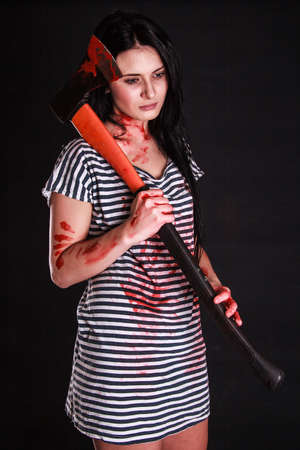 Young beautiful woman with a huge bloody axe over black background