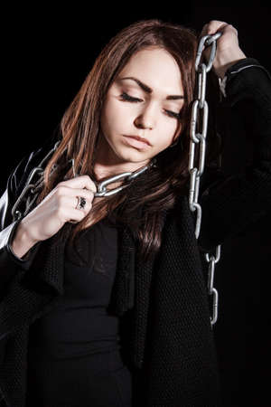 Beautiful young woman with chains over black backgroundの写真素材