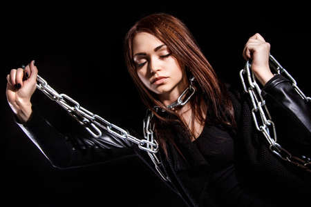 Beautiful young woman with chains over black backgroundの写真素材