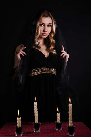 Mysterious young woman with candles in darkness