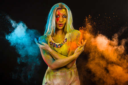 Young woman covered with paints over black background