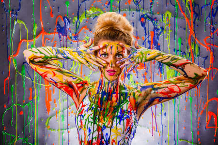 Beautiful young woman covered with multicolored paints