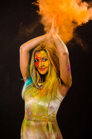 Beautiful young woman with colored powder over dark backgrondの写真素材