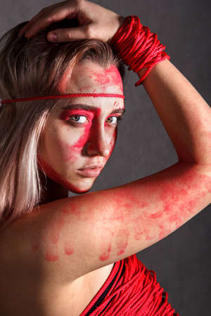 Beautiful young woman covered with red paintsの写真素材