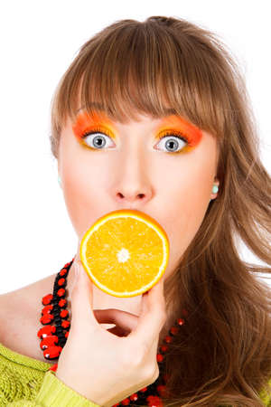 Cute young woman with an orange fruit in a mouth isolated over white backgroundの写真素材