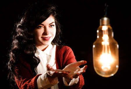 Pretty young woman looking to the light bulbの写真素材