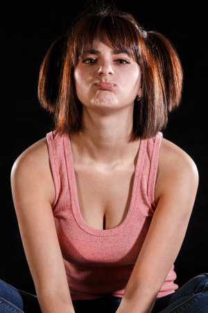 Pretty young girl making a grimace over black backgroundの写真素材
