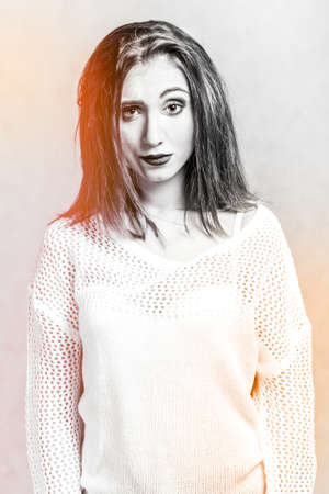 Misunderstanding young woman in a white sweater over grey background