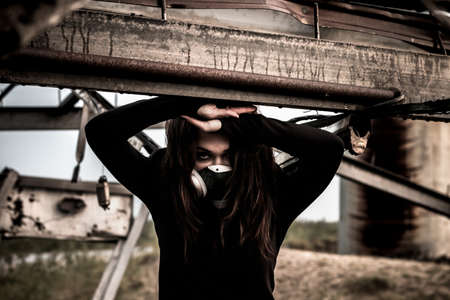 Woman in the gas mask inside the rusty structureの写真素材