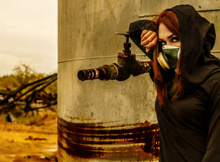 Woman in the gas mask at the background of the rusty structureの写真素材