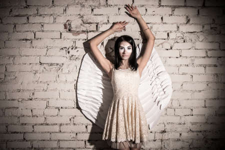 Pretty angel near the brick wall in darknessの写真素材