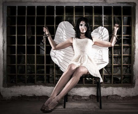 Pretty angel tied to the lattice in the dark の写真素材