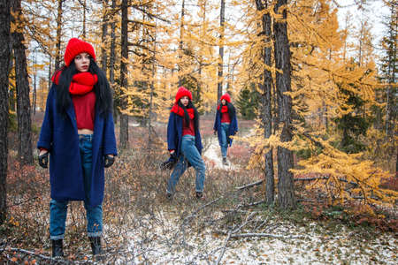 Pretty young woman in a red hat and scarf walking in the forestの写真素材