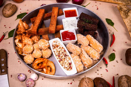 Plate of snacks at the background of the chilli pepper, cashew nuts and green leavesの写真素材