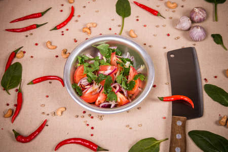 Sliced fresh tomatoes and onions at the background of the chili pepper, cashew nuts and green leavesの写真素材