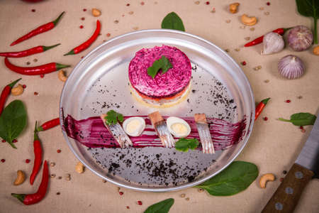 Dressed herring salad (herring under a fur coat) at the background of the chili pepper, cashew nuts and green leavesの写真素材