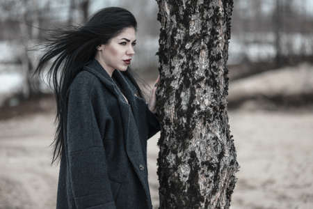 Serious young woman staying near the pine treeの写真素材