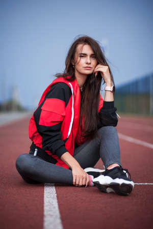 Sportive girl in a bright red jacket at the running trackの写真素材