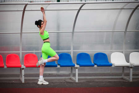 Young woman in a bright green training clothes near the football seats