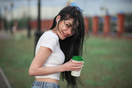Happy young woman with a cup of coffee outdoors