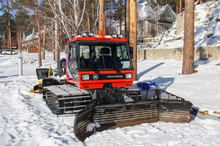 Miass, Russia - February 9, 2020: Snow groomer PistenBully PB 160 with a tiller and tracksetter in a pine wood.のeditorial素材