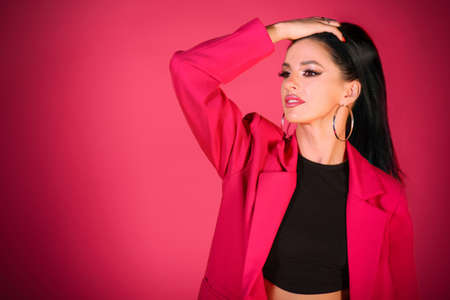 Stylish young woman in a bright pink suit over pink backgroundの写真素材
