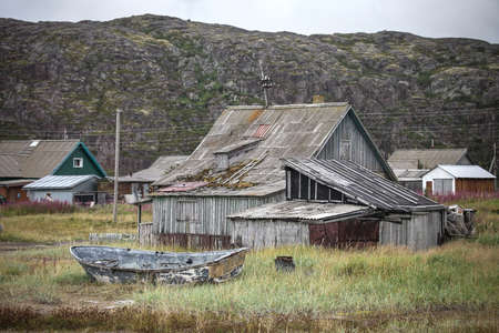 Broken boat near the abandoned wooden buildingの写真素材