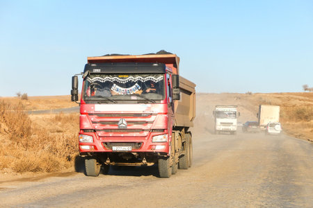 Aktobe Region, Kazakhstan - October 30, 2022: Red dump truck CNHTC Howo ZZ at a dusty road.のeditorial素材