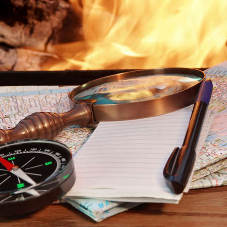Road maps, Compass,  Notebook, pen and a magnifying glass on the board by bonfireの写真素材