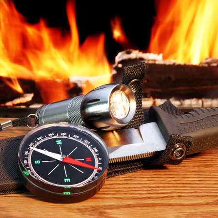 Compass, a hunting knife and a handheld flashlight around the campfireの写真素材