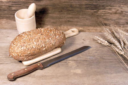 Cereal Bread Loaf with Grains and slicer knife in rustic still-life, with space for text or image