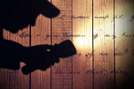 Male silhouete with serchlight on wooden wall  with unrecognizable text  Background with space for text or image の写真素材