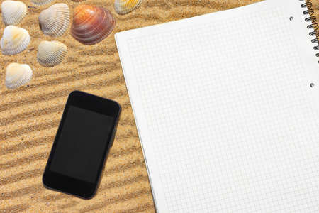White checkered notepad and  smartphone on the beach  Background with space for text or imageの写真素材