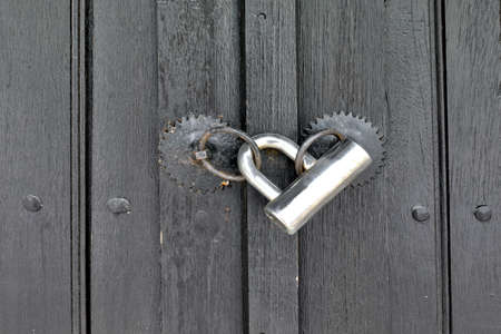Modern padlock on textured black wooden door. Background and Texture for text or image