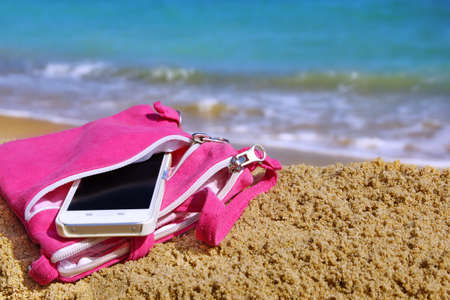 Almost Unrecognizable Smartphone In Pink Female Purse on The Summer Sea Beachの写真素材