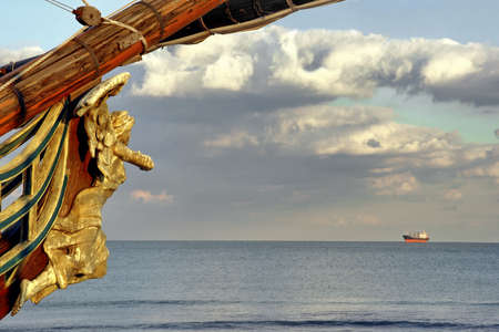Female Wooden Carved Figurehead found at the Prow of Old Ship. Modern ship at sea horizon.