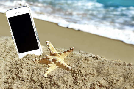 Starfish and Mobile Phone on the Summer Beach Close-up.の写真素材