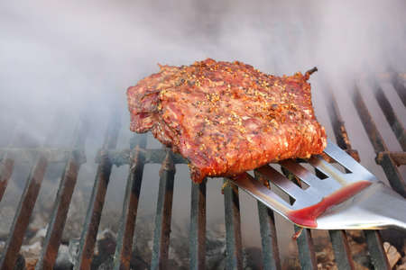 Spatula with Medium Rare Grilled Beef Steak. BBQ Grill and Smoke on the Background.の写真素材