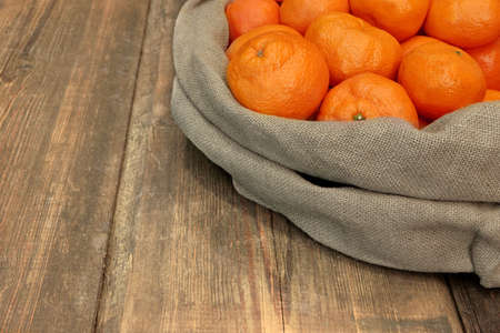 Ripe Tangerines  in Burlap Bag on Grunge Wood Tableの写真素材