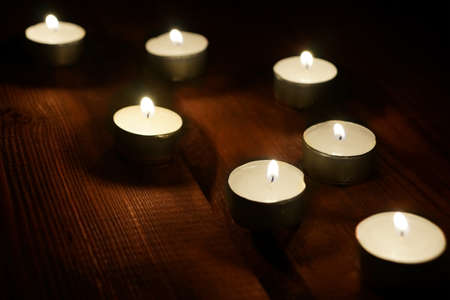 Seven Decorative Lighted Candles in Dark on Grunge Boardの写真素材