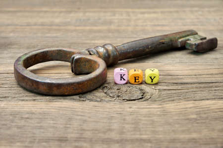 Old Rusty Iron Key and Sign KEY on a Wooden Backgroundの写真素材