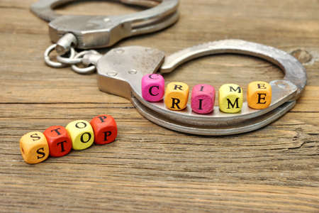 Sign Stop Crime and Handcuffs on Wooden Tableの写真素材