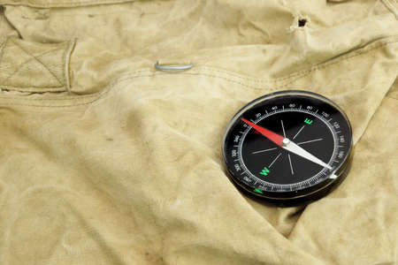 Modern Magnetic Compass,  Old Camouflage  Handbag or Backpack on the Background
