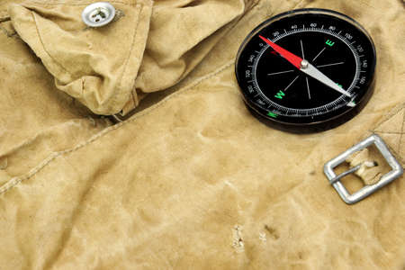 Modern Magnetic Compass,  Old Camouflage  Handbag or Backpack on the Background