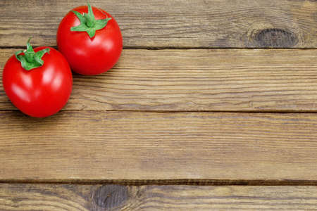 Two Ripe Shinny Fresh Tomatoes On Rough Rustic Wood Tabletopの写真素材